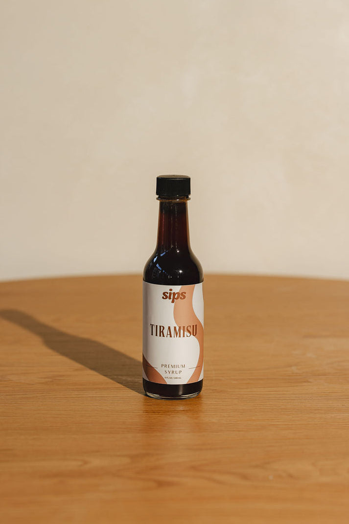 Bottle of Sips Tiramisu syrup on a wooden surface with a beige background